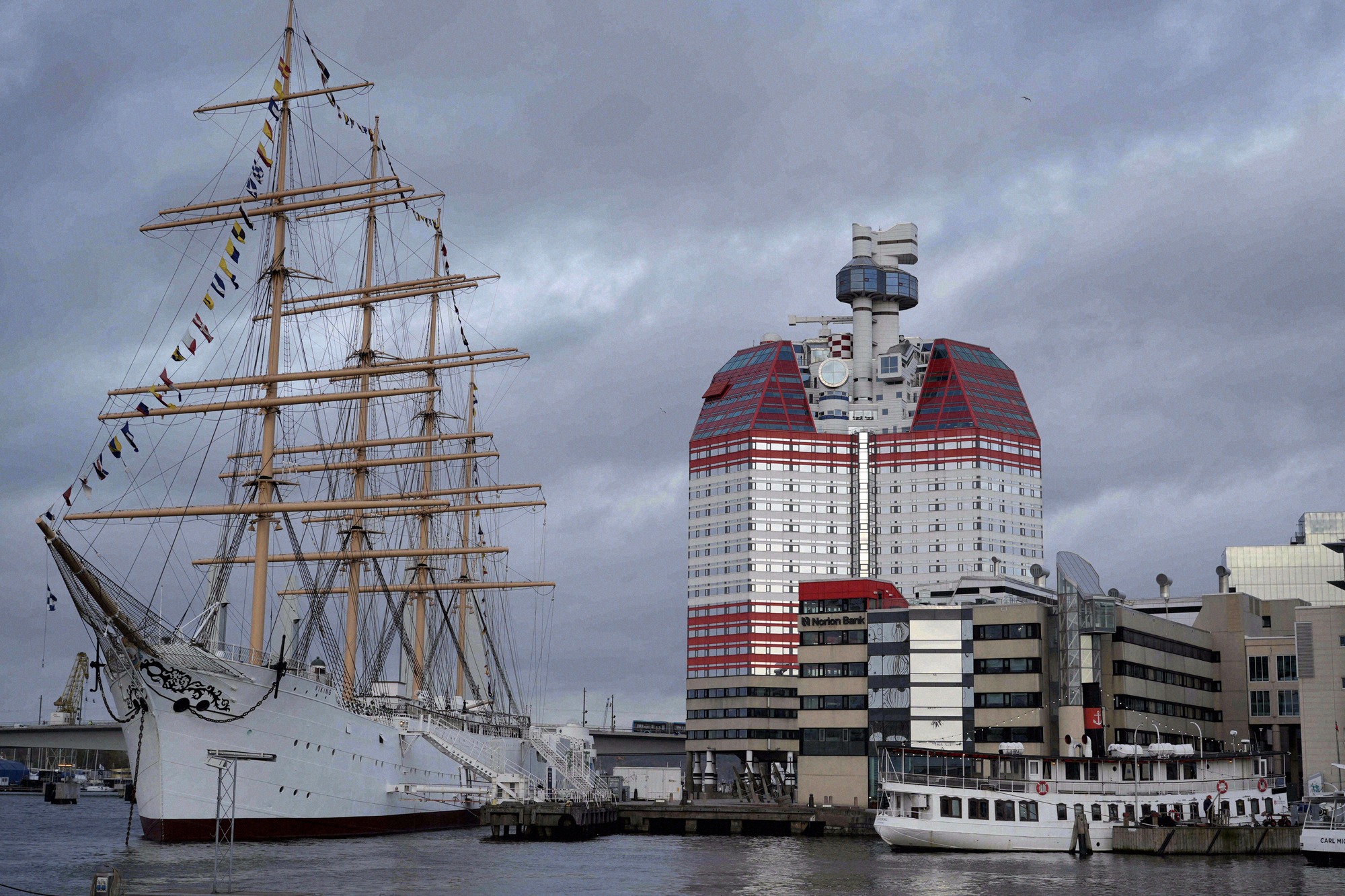 Das historische Vollschiff Barken Viking liegt am Göta älv vor dem charakteristischen roten Hochhaus Lila Bommen im Göteborger Hafen.